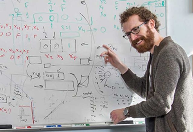 photo of grad student in front of writing on a whiteboard