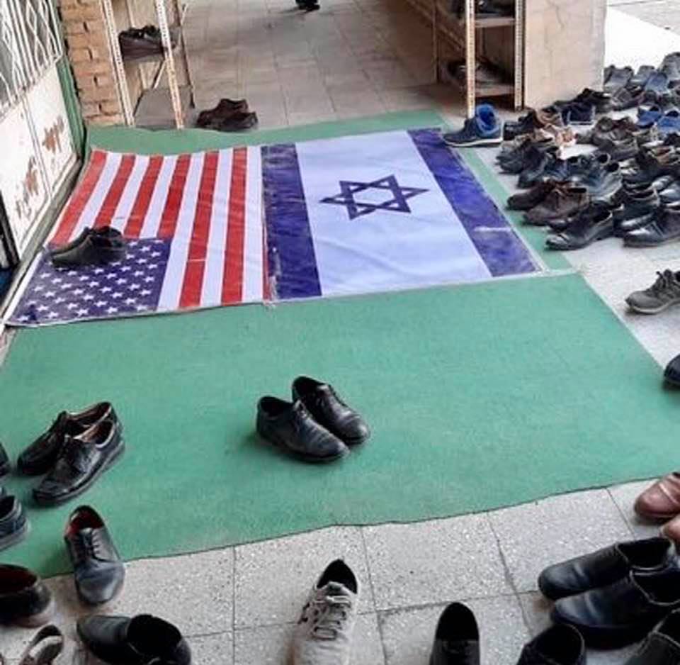 At a mosque's threshold, in the southern province of Khuzistan, worshippers avoid putting their shoes on the American and Israeli flags
