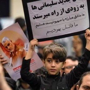 Iranian boy holding a sign that reads: 'We are future Ghasem Soleimanis. We kill the Jews'