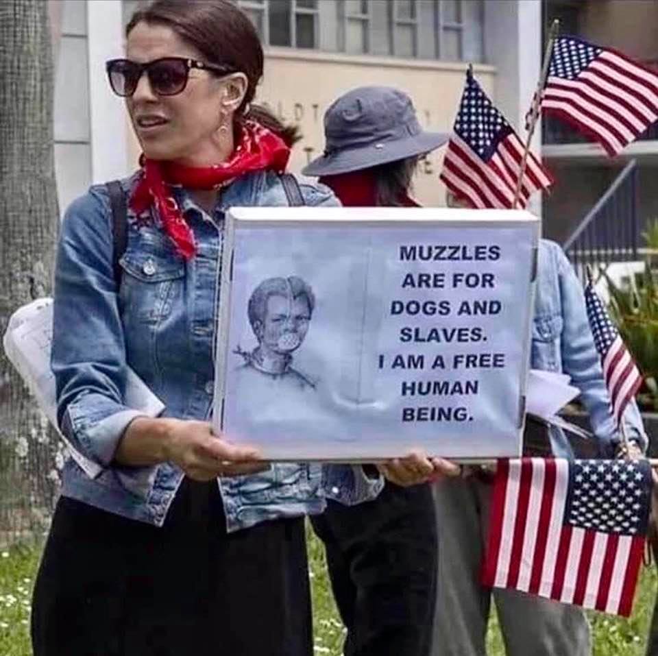 Woman protester holding a sign that reads 'Muzzles are for dogs and slaves' I am a free human being'
