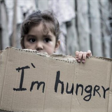 Young girl holding up a sign reading 'I'm hungry'