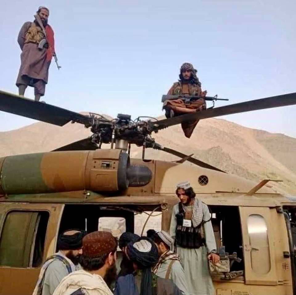 The Taliban sitting and standing on chopper rotor blades