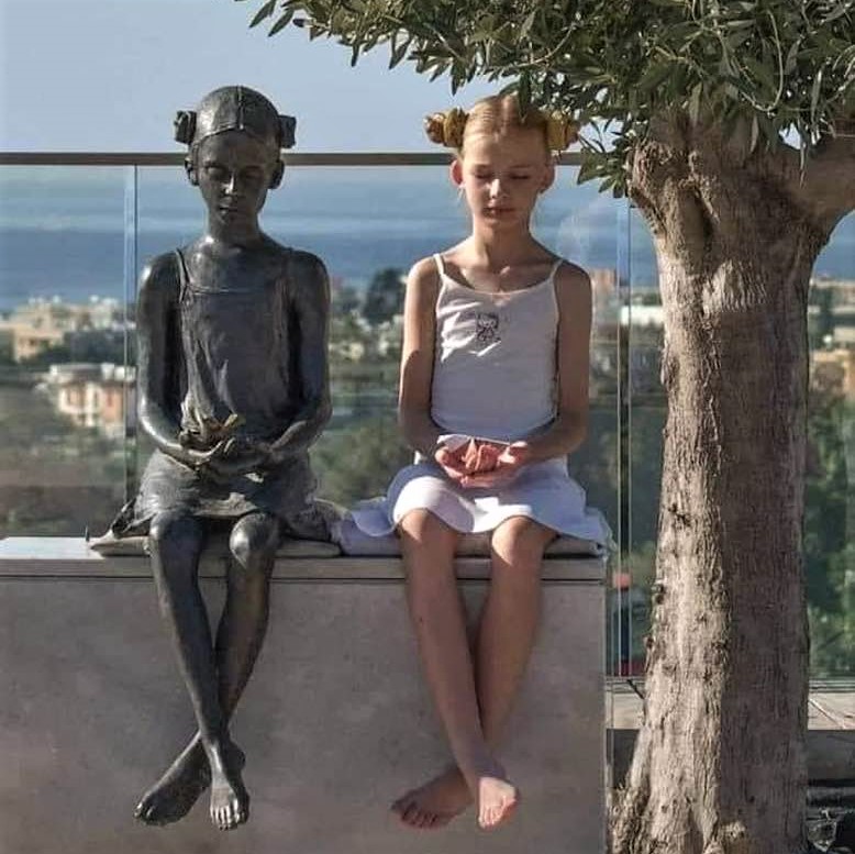 Life imitating art: Young girl emulates the pose of a statue