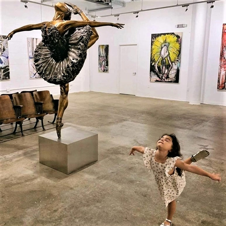 Little girl inspired by the statue of a ballerina